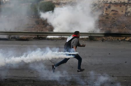 A Palestinian protester runs to return a teargas canister fired by Israeli troops during clashes near the Jewish settlement of Bet El, near the West Bank city of Ramallah, October 29, 2015. REUTERS/Mohamad Torokman