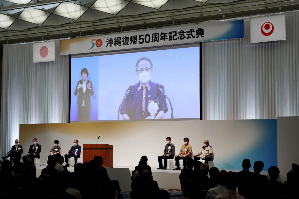 Governor of Okinawa Denny Tamaki, seen on a screen, delivers a speech during the ceremony to mark the 50th anniversary of Okinawa's return to Japan after 27 years of American rule Sunday, May 15, 2022, in Tokyo, Japan. The ceremony is held in Tokyo and Okinawa simultaneously for the first time. (Rodrigo Reyes Marin/Pool Photo via AP)