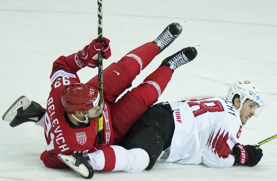 Andrei Belevich of Belarus, left, and Christoph Bertschy of Switzerland fight for a puck during the Ice Hockey World Championship group A match between the Belarus and Switzerland at the Olympic Sports Center in Riga, Latvia, Sunday May 30, 2021. (AP Photo/Roman Koksarov)