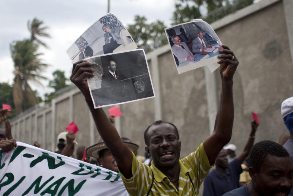 A demonstrator holds signs with images of former Haiti's President Jean Bertrand Aristide during a protest against Haiti's President Michel Martelly government in Port-au-Prince, Haiti, Sunday, Sept. 30, 2012. (AP Photo/Dieu Nalio Chery)