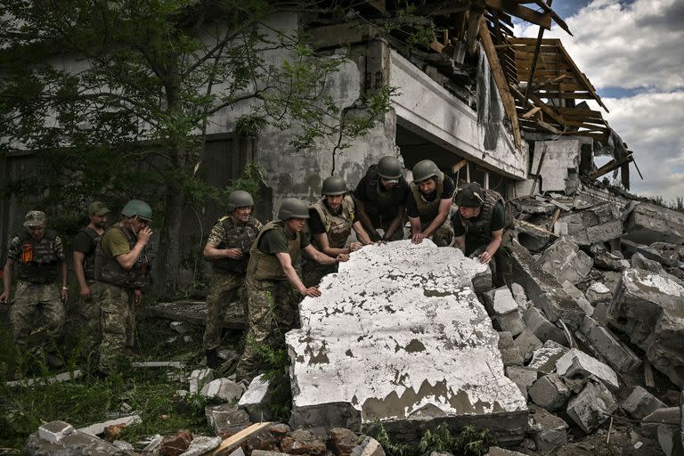 Soldados ucranianos inspeccionan un edificio destruido, atacado por tropas rusas en las afueras de Lysychansk, en la región oriental de Ucrania de Donbass, el 17 de junio de 2022, cuando la guerra ruso-ucraniana entra en su día 114. (Photo by ARIS MESSINIS / AFP)