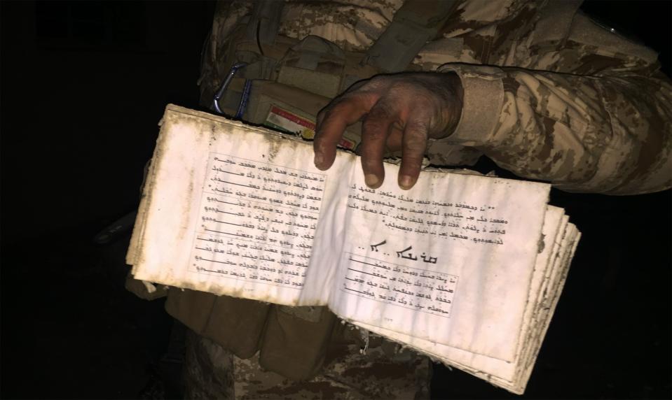 Christian peshmerga fighter holds open a Bible in the desecrated church of Batnay, Iraq. (Photo: Ash Gallagher for Yahoo News)