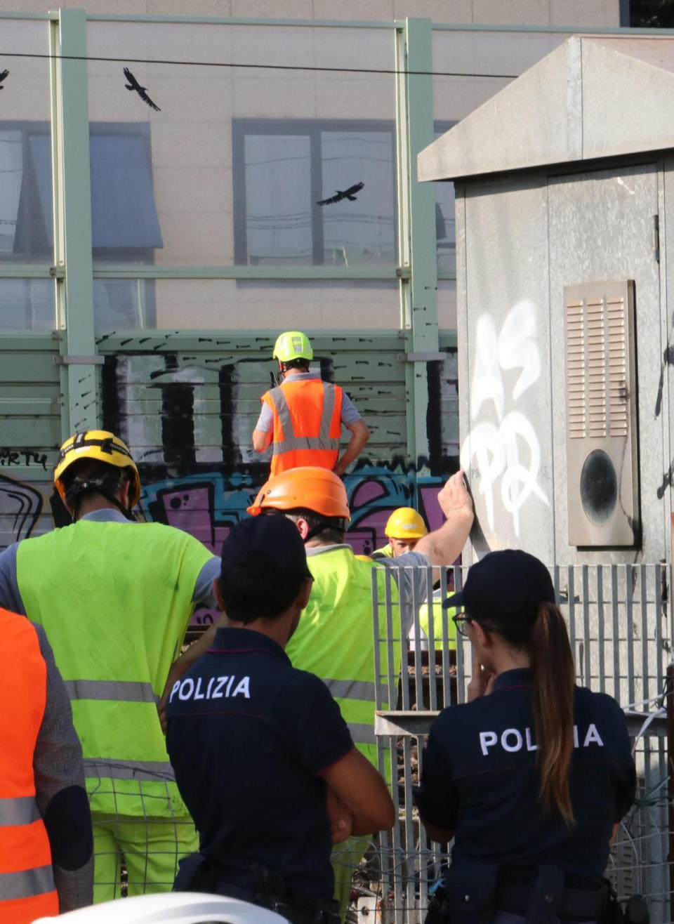 Police stand by as workers check electrical cables where a suspected arson fire occurred, on the tracks between Rovezzano and Campo di Marte train station, in Florence, Italy, Monday, July 22, 2019. The suspected arson fire has forced cancellations of at least 42 high-speed trains in Italy on the heavily-traveled Milan-Naples corridor. (Claudio Giovannini/ANSA via AP)