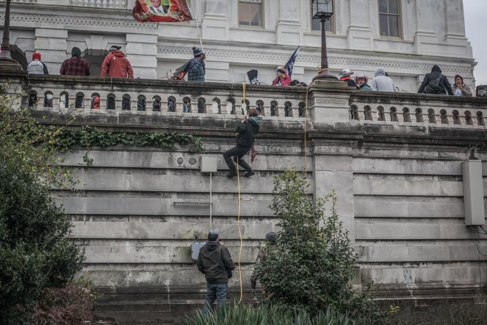 Trump supporters use ropes and barricades to scale a wall outside the US Capitol, January 06, 2021.