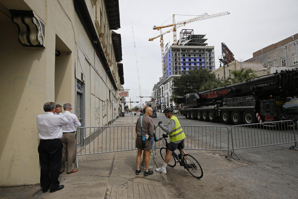 Passers-by watch and take pictures near the Hard Rock Hotel, Thursday, Oct. 17, 2019, in New Orleans. The 18-story hotel project that was under construction collapsed last Saturday, killing three workers. Two bodies remain in the wreckage. (AP Photo/Gerald Herbert)