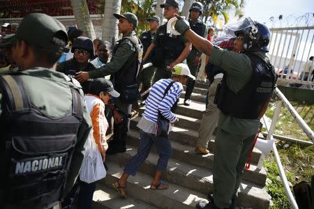 Miles de personas inundaban el viernes los supermercados y los mercados públicos de productos regulados de Venezuela tratando de conseguir bienes de primera necesidad después de una temporada navideña que arrasó con las provisiones y profundizó la escasez que vive el país, mientras el Gobierno desplegaba a policías militares para resguardar las enormes colas. En la imagen, policías controlan el acceso a uno de los mercados gubernamentales de la red de abastos de Caracas, el 9 de enero de 2015. REUTERS/Jorge Silva