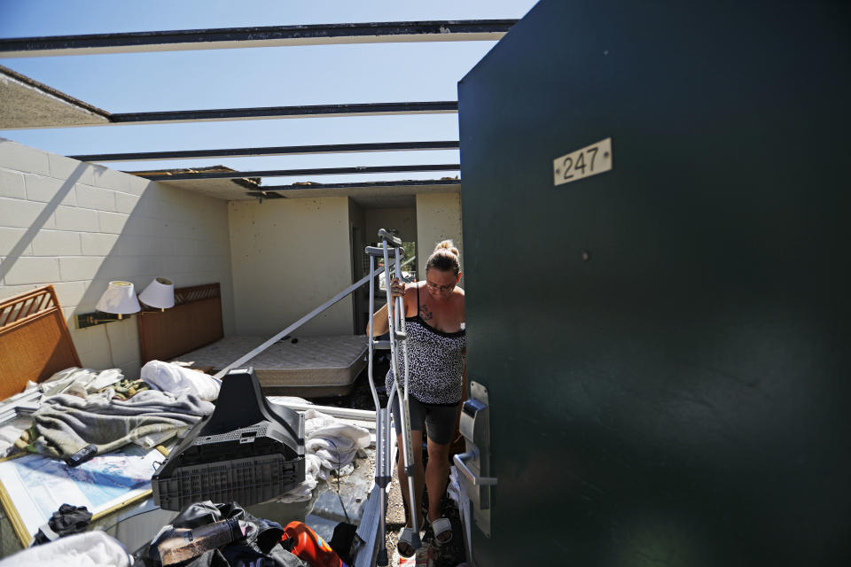 Jeannie Holcombe retrieves crutches for someone in need from a damaged room at the American Quality Lodge in the aftermath of Hurricane Michael, in Panama City, Fla., Tuesday, Oct. 16, 2018. Simply getting through the day is a struggle at the low-rent motel where dozens of people are living in squalor amid destruction left by the hurricane. (AP Photo/David Goldman)
