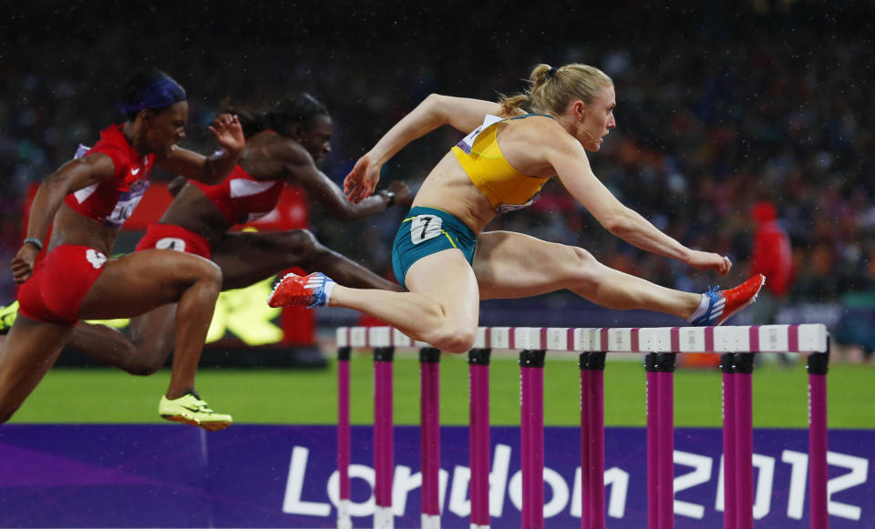 Australia's Sally Pearson (R) clears a hurdle ahead of Dawn Harper (C) and Kellie Wells of the U.S. in the women's 100m hurdles final during the London 2012 Olympic Games at the Olympic Stadium August 7, 2012. Pearson won gold and set a new Olympic record. REUTERS/Eddie Keogh (BRITAIN - Tags: SPORT OLYMPICS SPORT ATHLETICS TPX IMAGES OF THE DAY) 