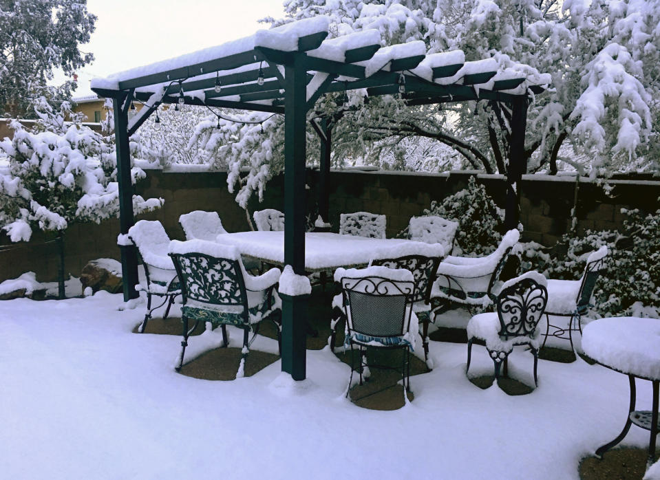 This photo provided by Pete Dugan shows snow covered patio furniture in the back yard of a home in Tucson, Ariz. on January 2, 2019. A winter storm has covered cactus with snow in parts of the American Southwest as temperatures in the desert fall below those of Anchorage, Alaska. (Pete Dugan via AP)