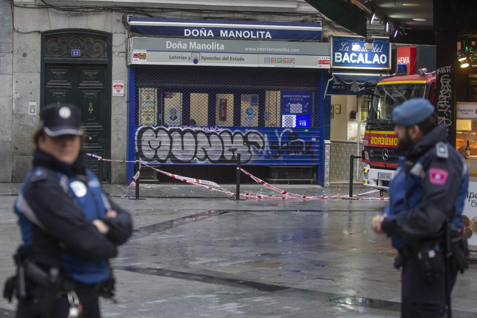 Police stand by the popular lottery sellers Dona Manolita, after it was closed and the area cordoned off due to a lose and unstable part of a high building caused by strong winds in Madrid, Spain, Saturday, Dec. 21, 2019. Spain's bumper Christmas lottery draw known as El Gordo, or The Fat One will be held on Dec. 22. (AP Photo/Paul White)