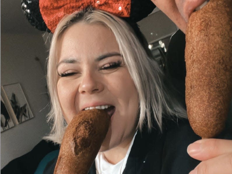 dana and her partner eating corn dogs at disneyland