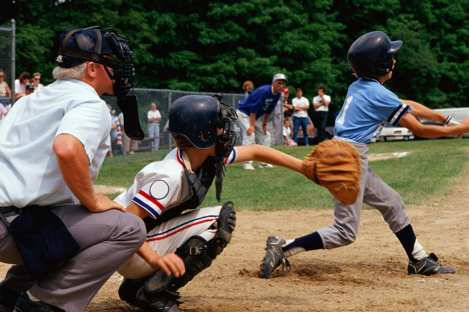 Kids playing little league, people watching, and umpire in the background