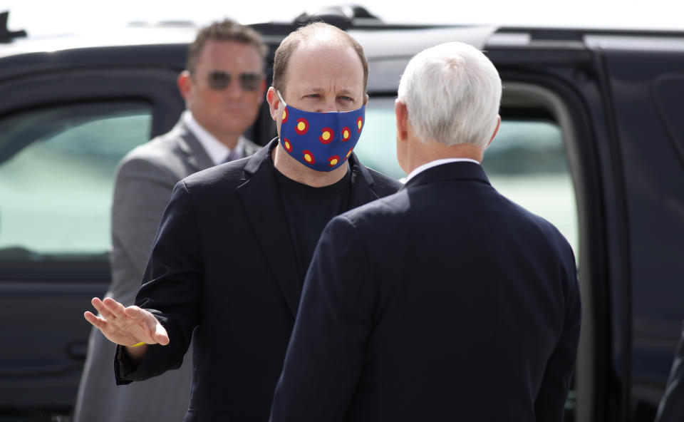 Gov. Jared Polis, center, wears a mask as he talks with Vice President Mike Pence as he arrives at Peterson Air Force Base Saturday, April 18, 2020, in Colorado Springs, Colo. Pence was on his way to speak at the graduation ceremony for the class of 2020 at the U.S. Air Force Academy. (AP Photo/David Zalubowski)