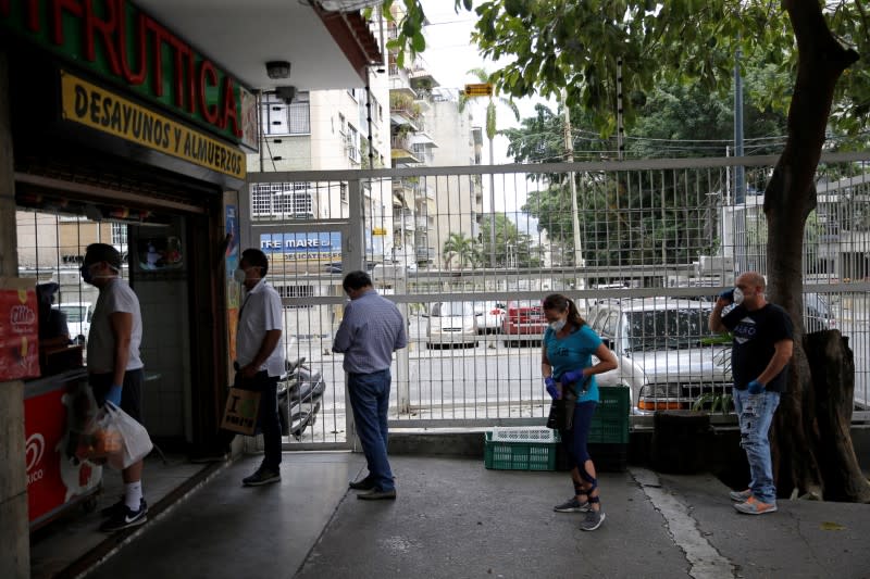Shoppers practice social distancing as they wait in line at a fruit shop during the national quarantine in response to the spread of coronavirus disease (COVID-19) in Caracas