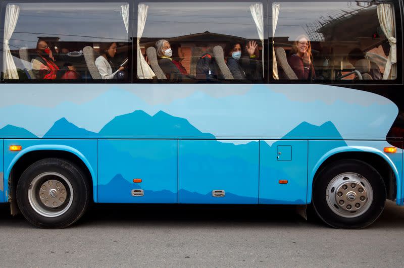 Stranded tourists from Germany greet members of the media from a bus as they leave for the airport in Kathmandu