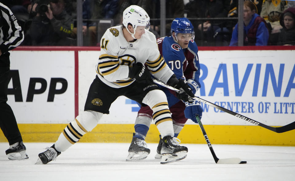 Boston Bruins center Trent Frederic, left, fights for control of the puck with Colorado Avalanche defenseman Sam Malinski (70) in the first period of an NHL hockey game Monday, Jan. 8, 2024, in Denver. (AP Photo/David Zalubowski)