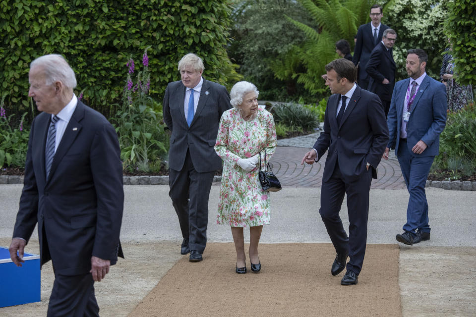 Queen Elizabeth II speaking with French President Emmanuel Macron as British Prime Minister Boris Johnson looks on, as they make their way for a group photo before a reception at the Eden Project during the G7 summit in Cornwall. Picture date: Friday June 11, 2021.