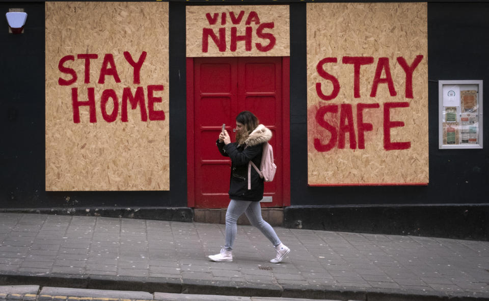 A woman walks past a boarded up restaurant in Edinburgh's Old Town as the UK continues in lockdown to help curb the spread of the coronavirus.