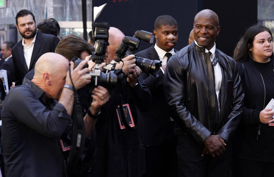 Terry Crews, right, a guest at the premiere of the film "John Wick: Chapter 4," watches photographers Monday, March 20, 2023, at the TCL Chinese Theatre in Los Angeles. (AP Photo/Chris Pizzello)