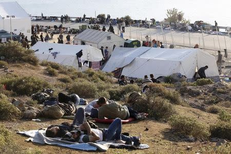 Refugees and migrants, who reached Greece after crossing part of the Aegean sea from Turkey, rest next to tents set by the United Nations refugee agency (UNHCR), on the Greek island of Lesbos, October 27, 2015. REUTERS/Giorgos Moutafis