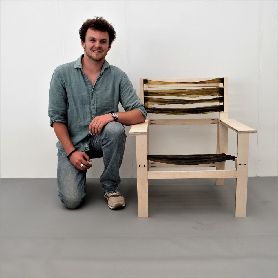 portrait of young furniture designer crouching by chair from green grads 2023 event