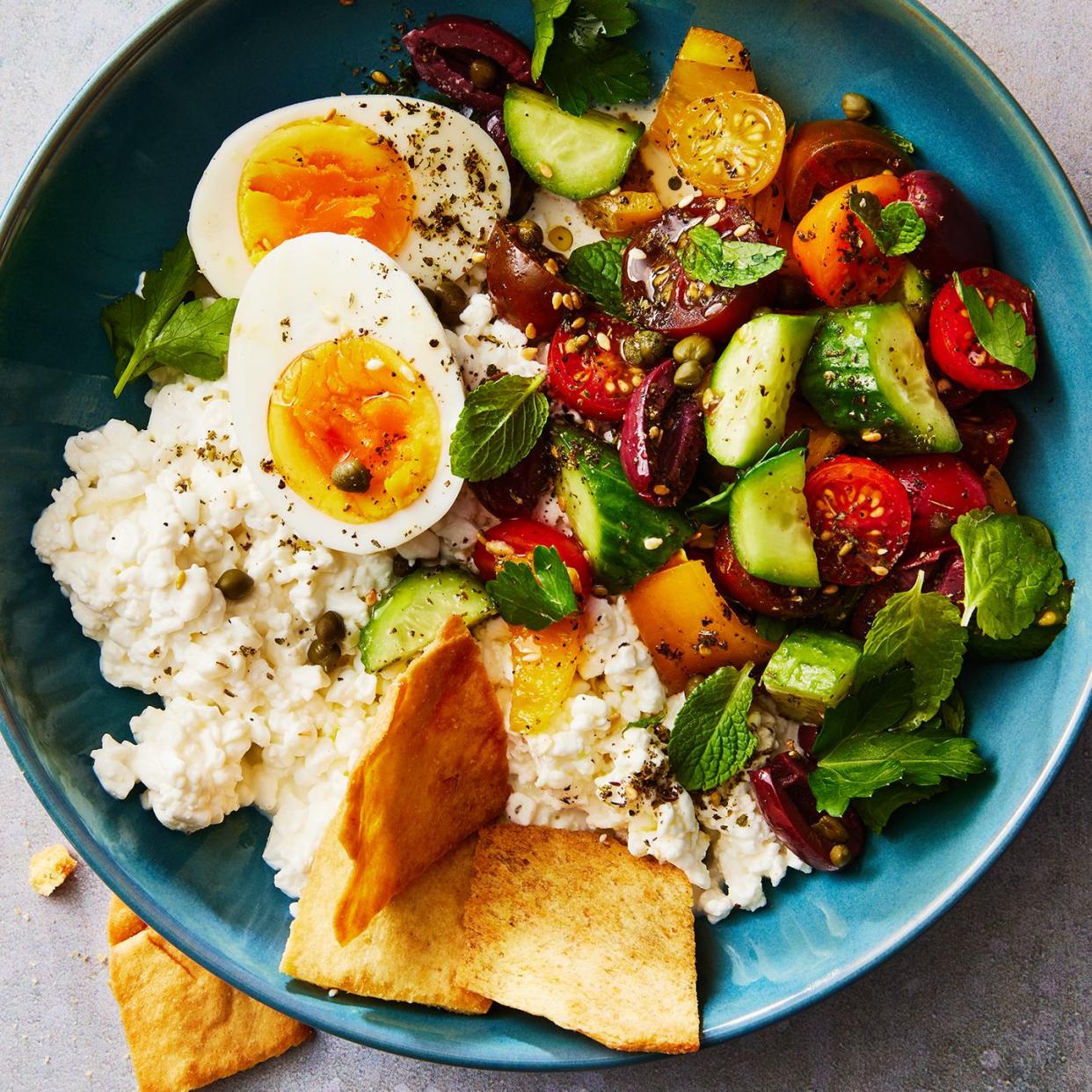 cottage cheese, soft boiled eggs, and a cucumber tomato salad topped with pita chips