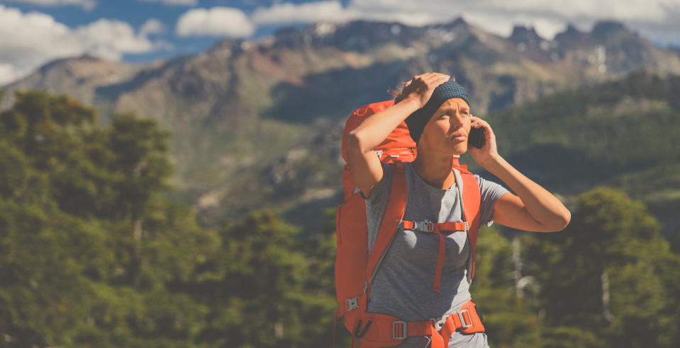 A hiker on the phone on top of a mountain