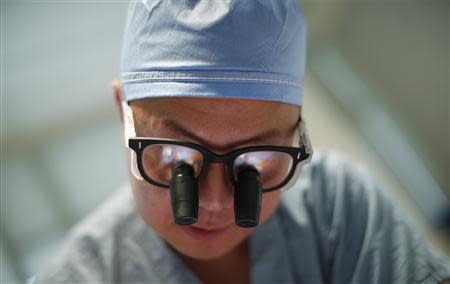 Doctor Andy Chiou debrides a leg wound on patient Larry Kirk in Peoria, Illinois, November 26, 2013. REUTERS/Jim Young