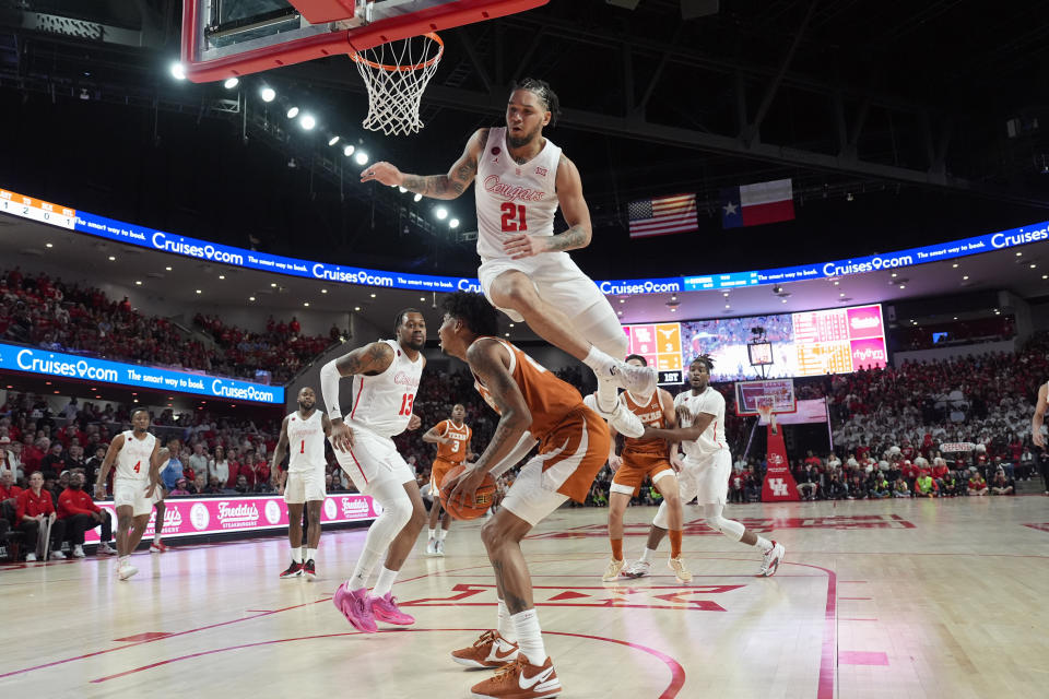 Houston's Emanuel Sharp (21) leaps over Texas' Dillon Mitchell during the first half of an NCAA college basketball game Saturday, Feb. 17, 2024, in Houston. (AP Photo/David J. Phillip)