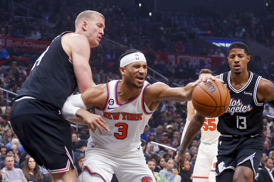 New York Knicks guard Josh Hart, center, struggles with the ball while defended by Los Angeles Clippers forward Mason Plemlee, left, during the first half of an NBA basketball game Saturday, March 11, 2023, in Los Angeles. (AP Photo/Ringo H.W. Chiu)
