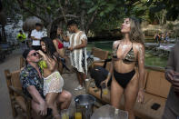 Tourists wear decorative body paint at a bar on the edge of a cenote in Tulum, Mexico, Saturday, March 2, 2024. Construction of the Maya Train is rapidly destroying part of the hidden underground world of caverns and sinkhole lakes, known as cenotes, already under threat by development and mass tourism. (AP Photo/Rodrigo Abd)