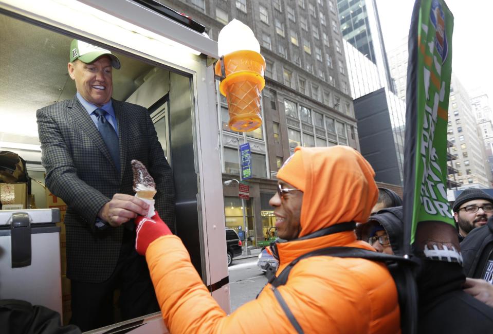 New York Jets head coach Rex Ryan, left, hands out free ice cream from a truck Friday, Jan. 31, 2014 on Broadway in New York. Ryan was taking part in an "Embrace the Cold" promotion by the New Era Cap Company to promote their Super Bowl merchandise. The Seattle Seahawks will play the Broncos Sunday in the NFL Super Bowl XLVIII football game in East Rutherford, N.J. (AP Photo/Ted S. Warren)