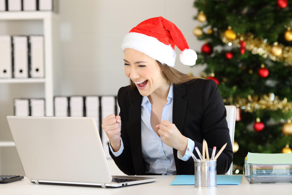 Excited office worker receiving good news on line in a laptop in christmas time