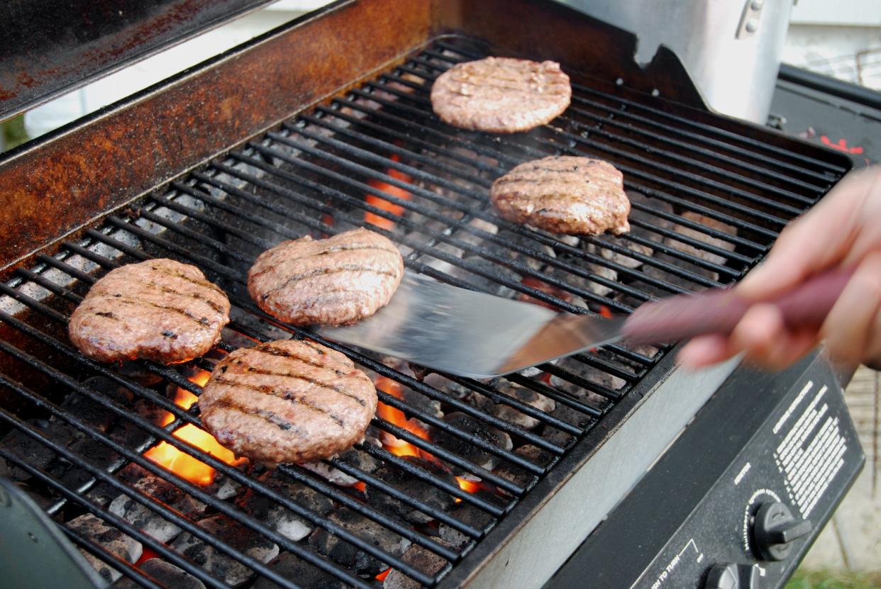 Flipping hamburgers on a barbecue grill.
