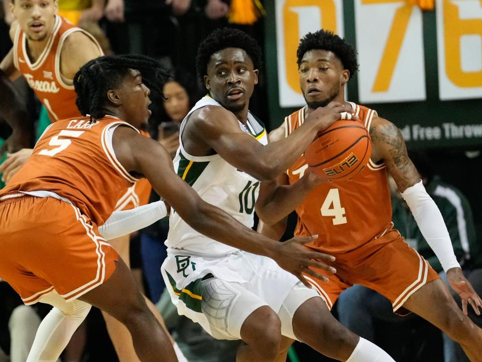 Texas defenders close in on Baylor guard Adam Flagler, who looks to pass during the first half. Texas fell to 9-5 in the Big 12. “We don't view it as a setback,” said forward Dylan Disu, who scored a Texas-best 24 points. “We definitely wanted to win this game, but we're just trying to get better with every game to get stronger as we go into March.”