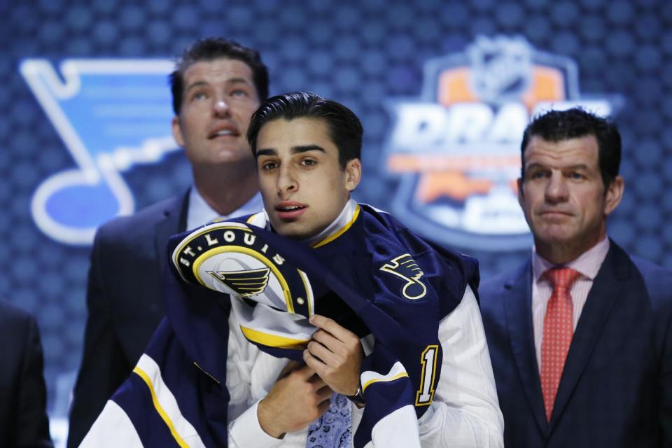 Robert Fabbri pulls on a St. Louis Blues sweater after being chosen 21st overall during the first round of the NHL hockey draft, Friday, June 27, 2014, in Philadelphia. (AP Photo/Matt Slocum)