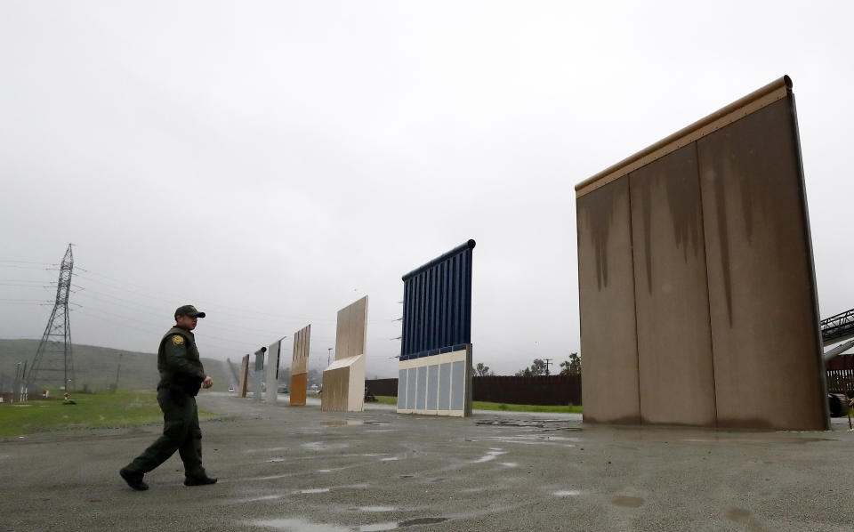 FILE - In this Feb. 5, 2019, file photo, a Border Patrol agent walks towards prototypes for a border wall in San Diego. The prototypes were taken down in February. (AP Photo/Gregory Bull, File)