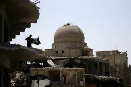 A member of Iraqi security forces holds a flag of Islamic State militants on the top of a destroyed building from clashes in the Old City of Mosul, Iraq, July 10. 

REUTERS/Thaier Al-Sudani