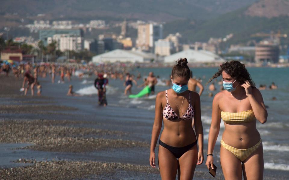 Women wearing face masks walk along Malaga's Misericordia Beach - Jorge Guerrero/AFP via Getty Images