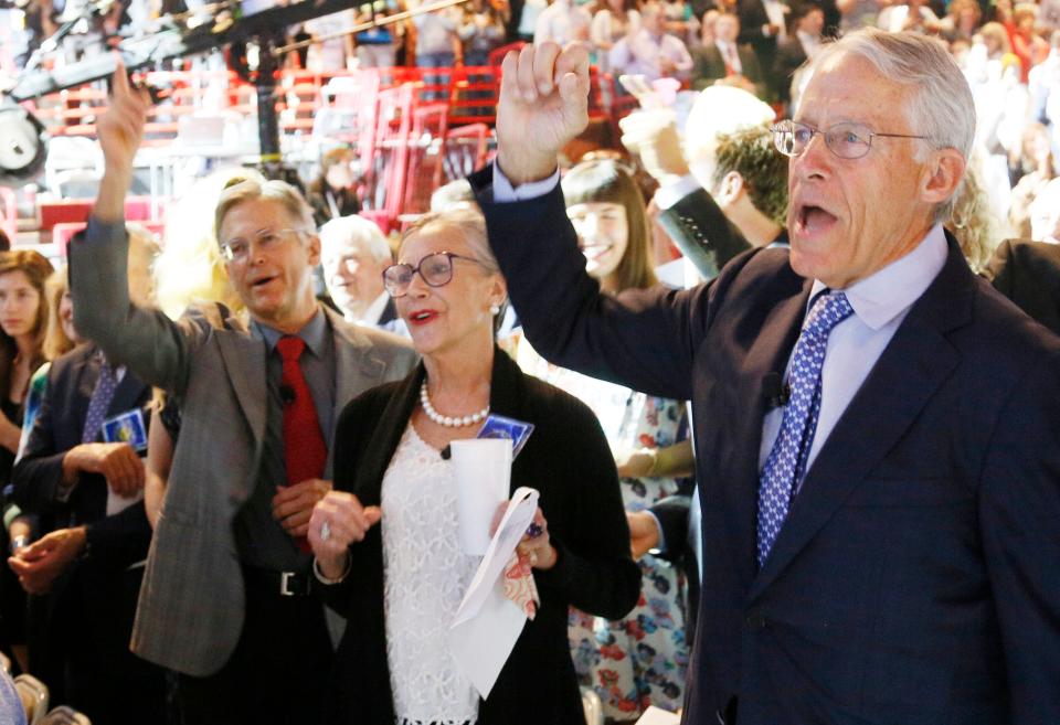 Jim Walton, Alice Walton, and Rob Walton cheering in a crowd.