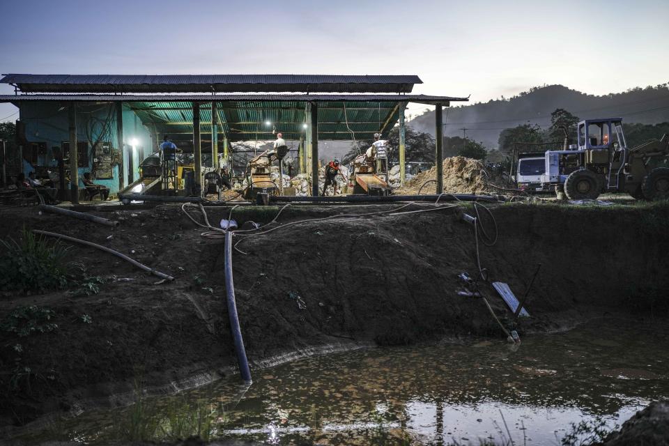 Workers crush rock at a gold mill in El Callao, Bolivar state, Venezuela, Friday, April 28, 2023. Operators use dynamite to loosen rocks below the surface, where workers descend to work in high heat with no safety gear. (AP Photo/Matias Delacroix)