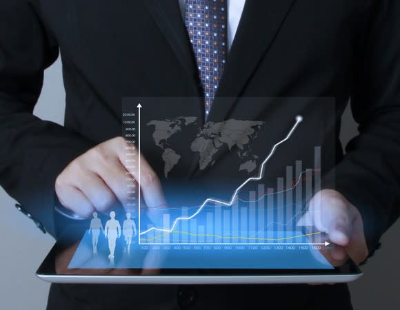 Man in suit touching a tablet screen with chart coming off of it