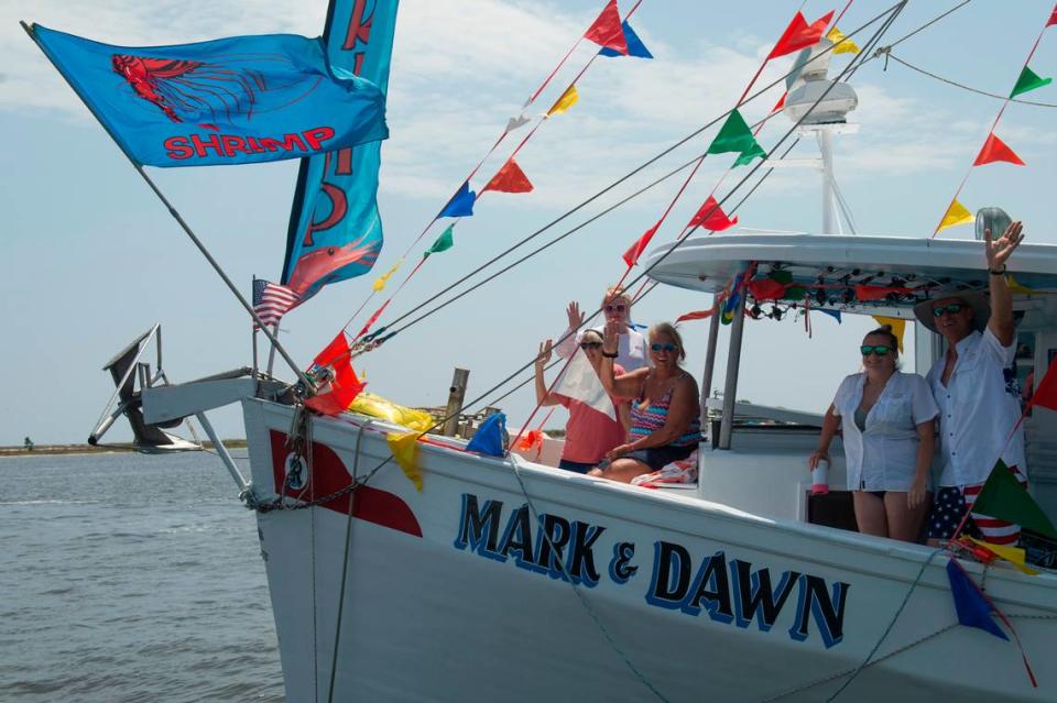 People on a boat wave to Msgr. Dominick Fullam and the Shrimp King and Queen as they receive a blessing during the Blessing of the Fleet in Biloxi on Sunday, May 28, 2023.