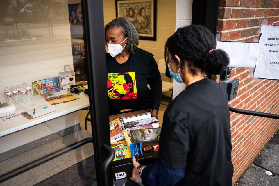 Cheryl Mayes, left, and Adrianne Gott, right, carry in a box of donated books during a book drive presented by The Interdenominational Ministers Fellowship at Jefferson Street Missionary Baptist Church in Nashville, Tenn., Monday, Jan. 17, 2022.