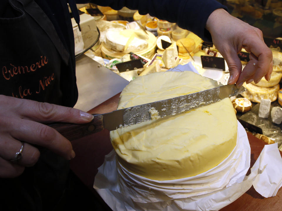 Una mujer corta mantequilla en un mercado en Francia (AP Foto/Bob Edme)