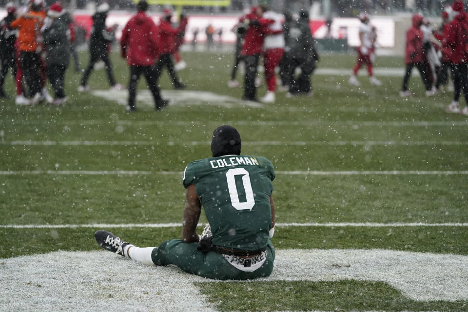 Michigan State wide receiver Keon Coleman sits in the end zone as Indiana celebrates the win after the second overtime of an NCAA college football game, Saturday, Nov. 19, 2022, in East Lansing, Mich. (AP Photo/Carlos Osorio)