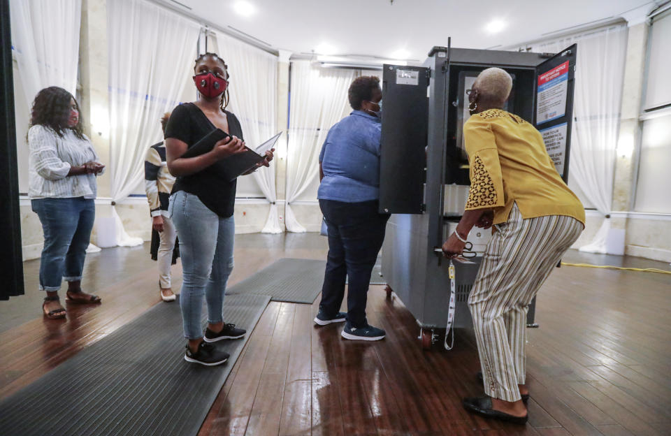 FILE - In this Tuesday, Aug. 11, 2020, file photo, poll workers prepare voting machines at Park Tavern amid the coronavirus pandemic, in Atlanta. A federal judge has ordered Georgia to extend its deadline for accepting mail-in ballots for November’s general election from the close of polls on Election Day until three days later. The secretary of state's office says it plans to immediately appeal the ruling. (John Spink/Atlanta Journal-Constitution via AP, File)