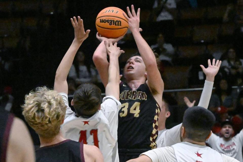 Sierra’s Logan Kilbert, center, takes a shot guarded by North’s Nate Becerra in the Central Section Division III Boys basketball championship Saturday, Feb. 24, 2024 at Selland Arena in Fresno..