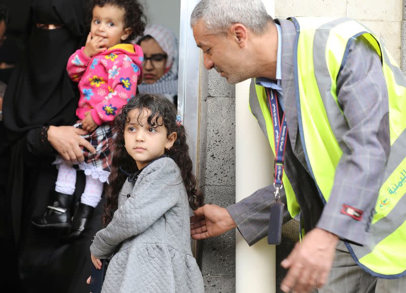 Airport worker helps a girl before her boarding on a United Nations plane which will carry her and other patients to Amman, Jordan in the first flight of a medical air bridge from Sanaa, Yemen