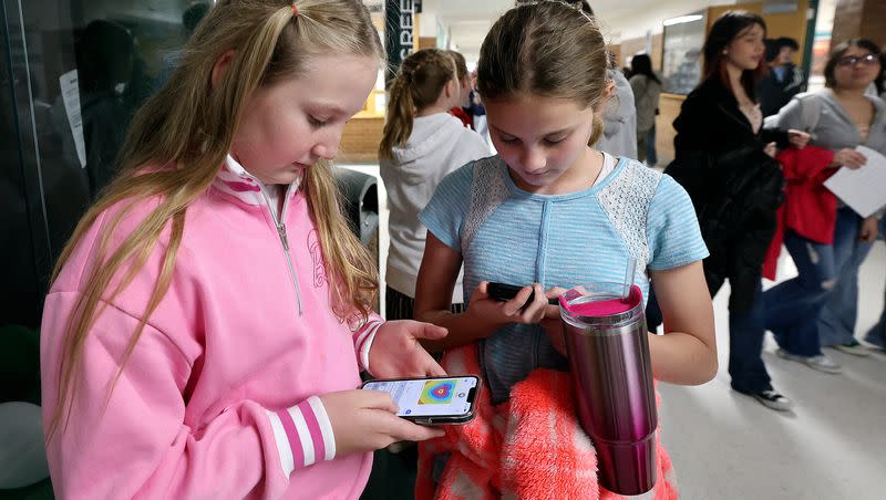 Sixth graders Ashton Wiggins and Aspen Pace use their cellphones after school at Evergreen Junior High School in Millcreek on Wednesday, Jan. 10, 2024. Phones are banned at Evergreen during the school day but are allowed after the final bell rings.